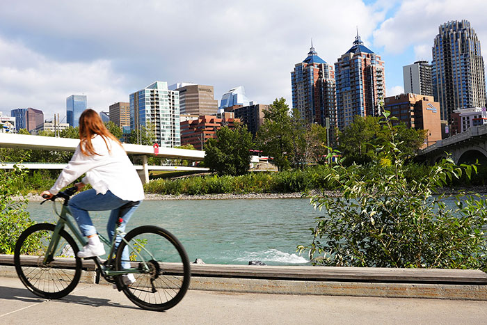 A woman rides her bike along the bow river pathway in downtown Calgary